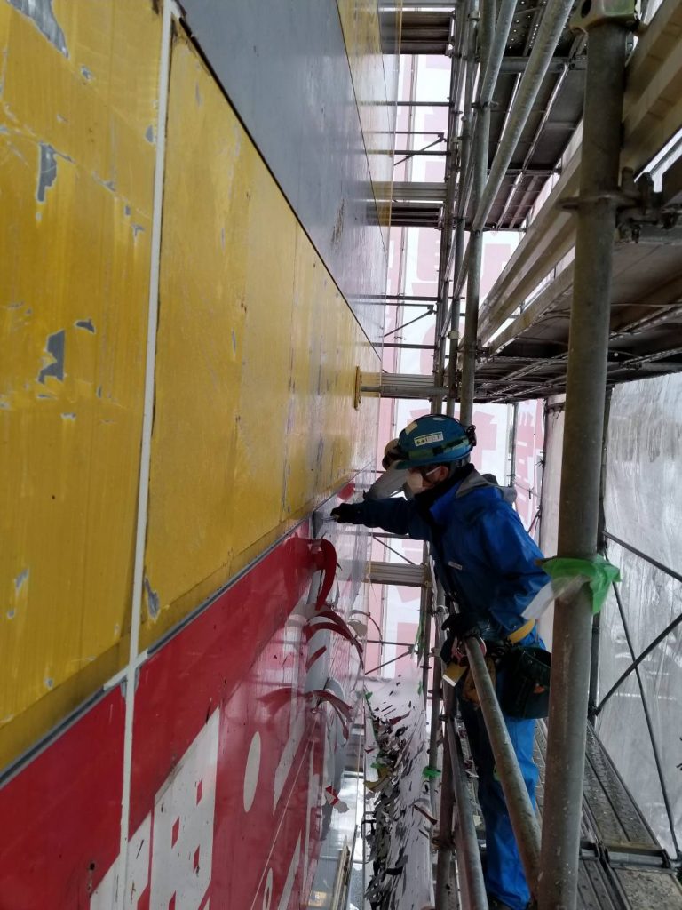 大型壁面サインを足場の上で剥がし作業